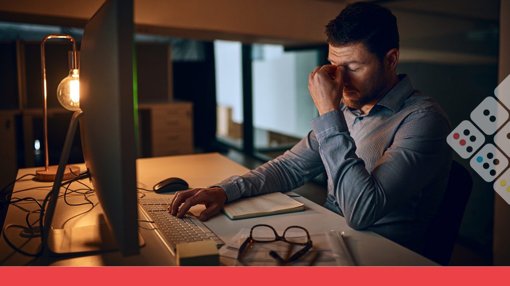 Trabajador frente a computadora cansado por jornada laboral